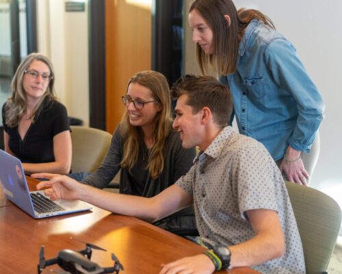 Office workers sitting around computer
