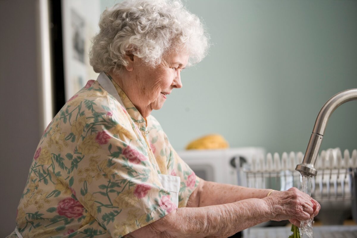 elderly woman at kitchen sink